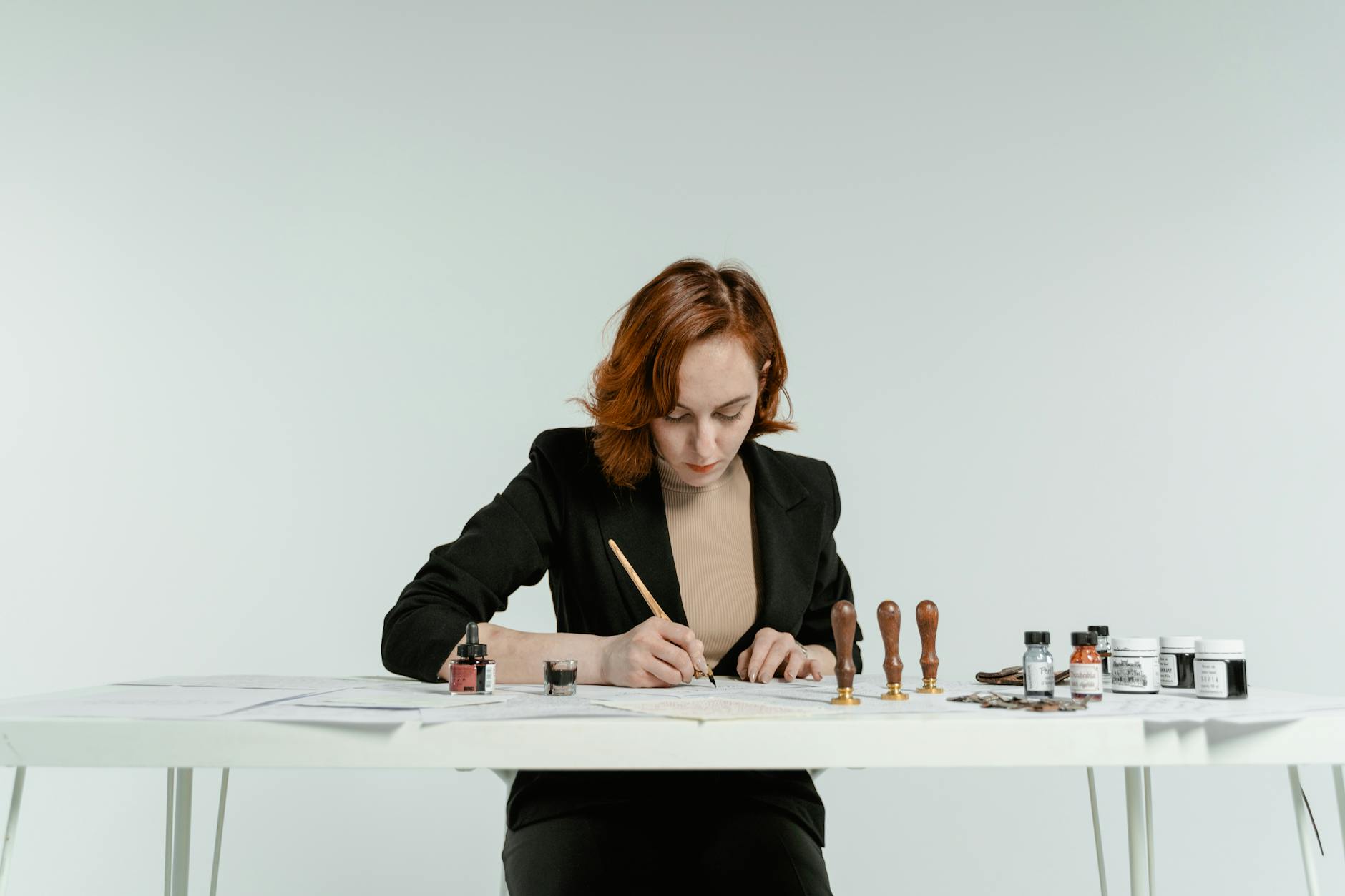 Kobieta przy biurku ćwiczy kaligrafię na białej kartce