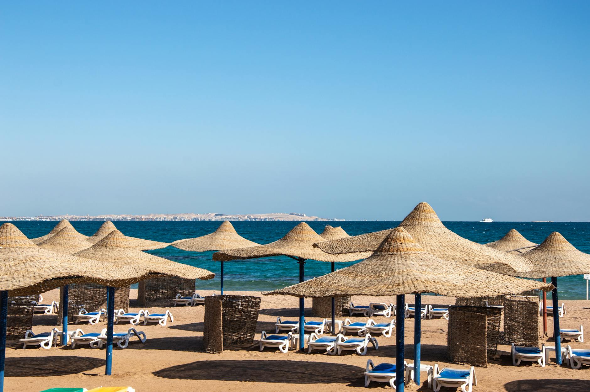 Pusta plaża w Egipcie zimą z parasolami i leżakami nad spokojnym morzem