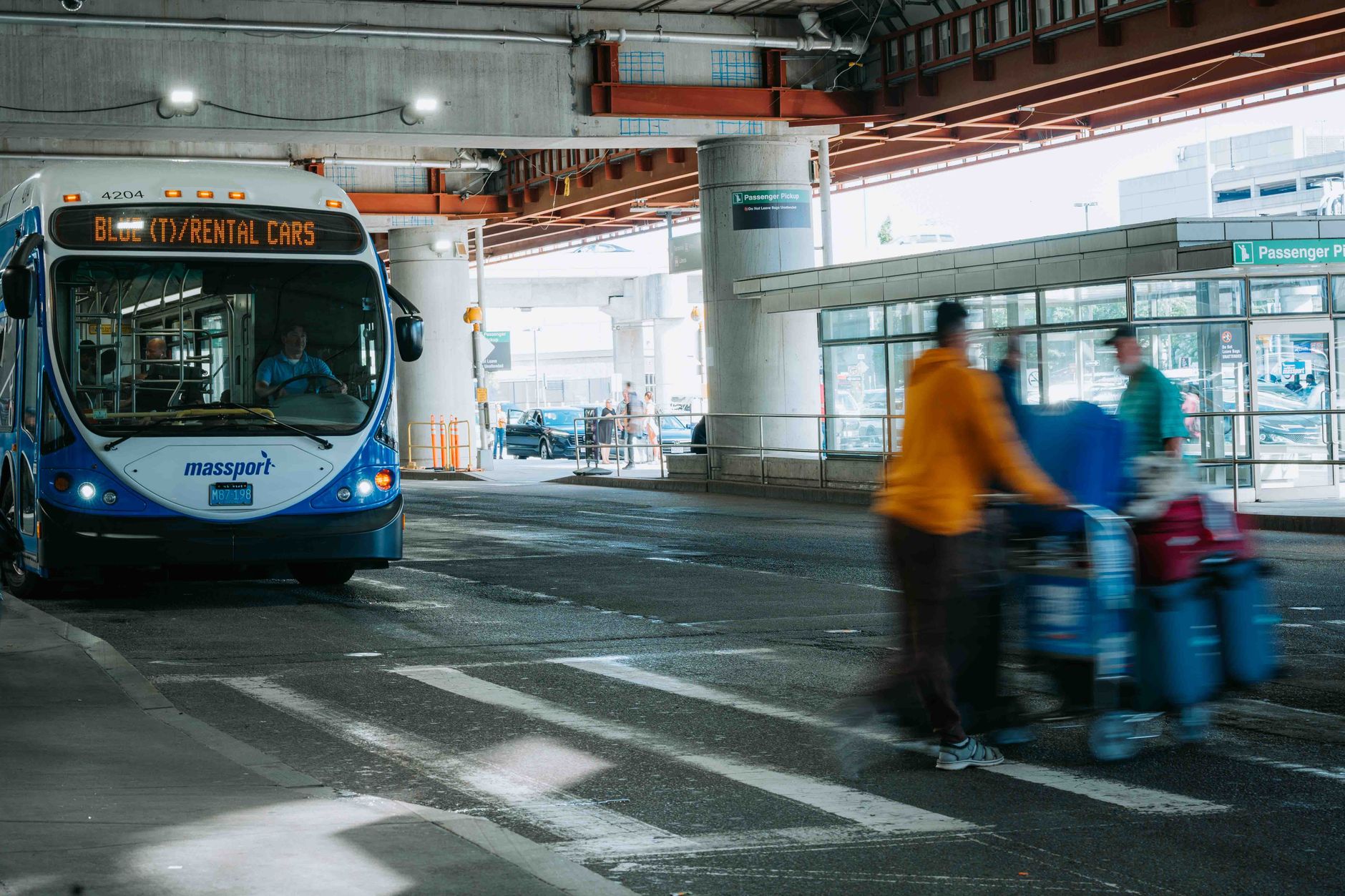 Podróżni na lotnisku i autobus wypożyczalni pod zadaszonym terminalem